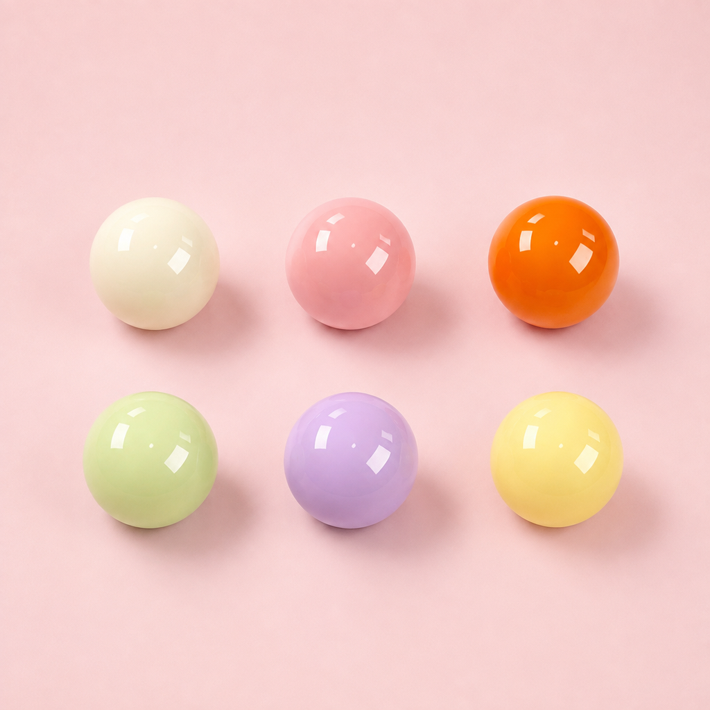 Nahaufnahme von sechs glänzenden, bunten Perlen-Charms in Pastel-Tönen für das Hundehalsband Bonbon Glück von Mops Berlin vor rosafarbenem Hintergrund.
