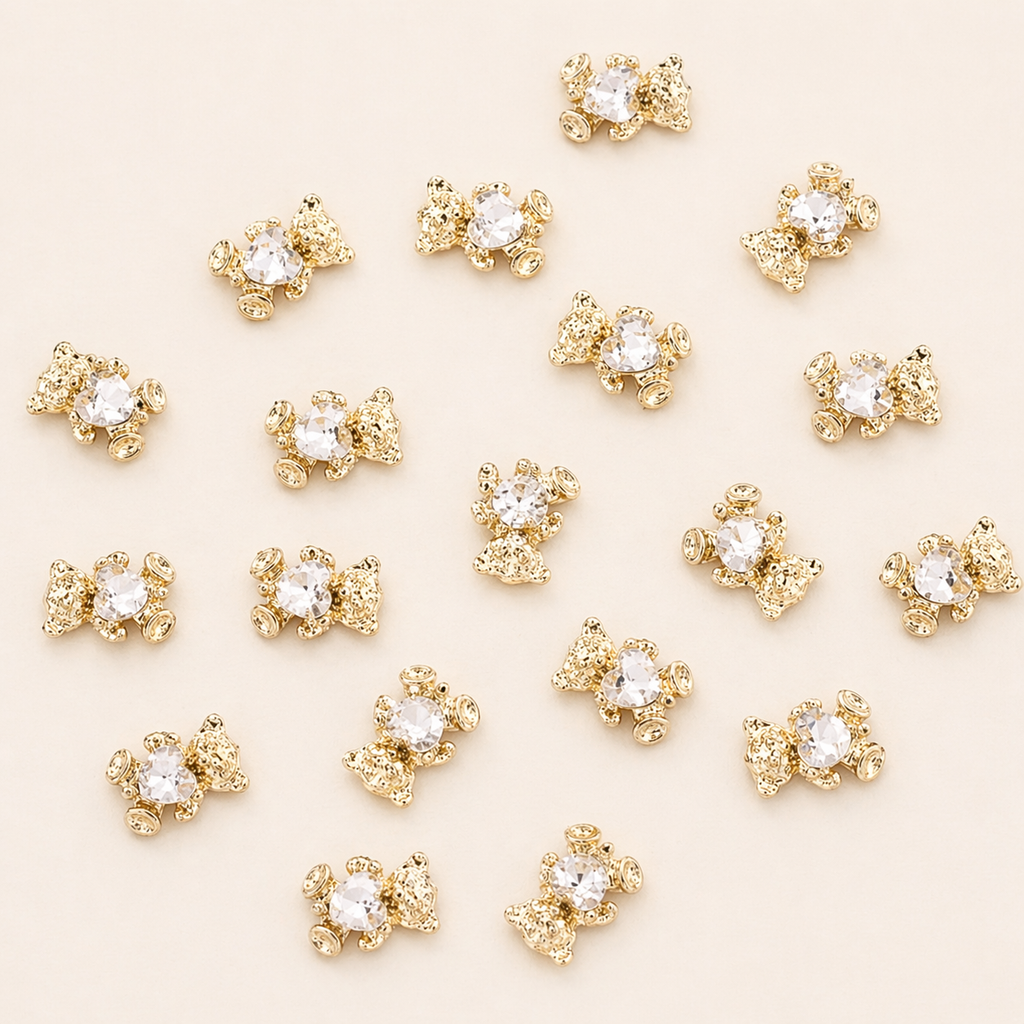 Nahaufnahme der goldenen Bären-Charms mit funkeldem Glitzerstein für das Hundehalsband Goldbär von Mops Berlin arrangiert auf beigefarbenem Hintergrund.