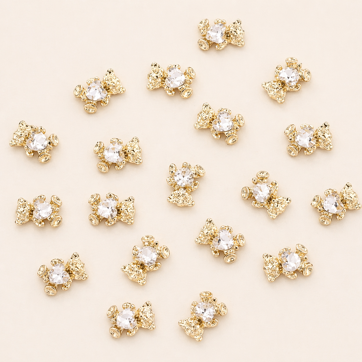 Nahaufnahme der goldenen Bären-Charms mit funkeldem Glitzerstein für das Hundehalsband Goldbär von Mops Berlin arrangiert auf beigefarbenem Hintergrund.