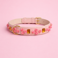 Handgefertigtes Hundehalsband Nelken Traum aus rosafarbenem veganen Leder mit pinken Blütendetails, amberfarbenen Steinen und goldener Schnalle von Mops Berlin auf rosa Hintergrund.