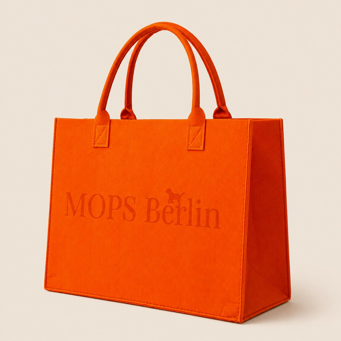 Schräge Seitenansicht der orangefarbenen Filztasche von MOPS Berlin mit eingeprägtem Logo und stabilen Tragegriffen vor hellem Hintergrund