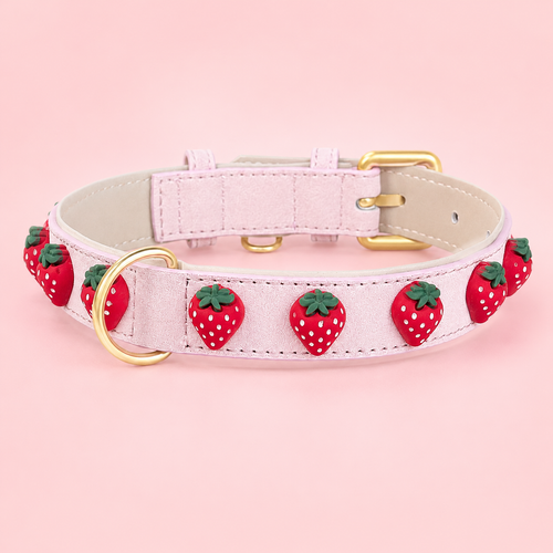 Quadratisches Produktfoto des Mops Berlin Hundehalsbands Erdbeersommer aus rosafarbenem veganem Leder, verziert mit roten Erdbeer-Applikationen sowie goldener Schnalle und D-Ring vor rosa Hintergrund