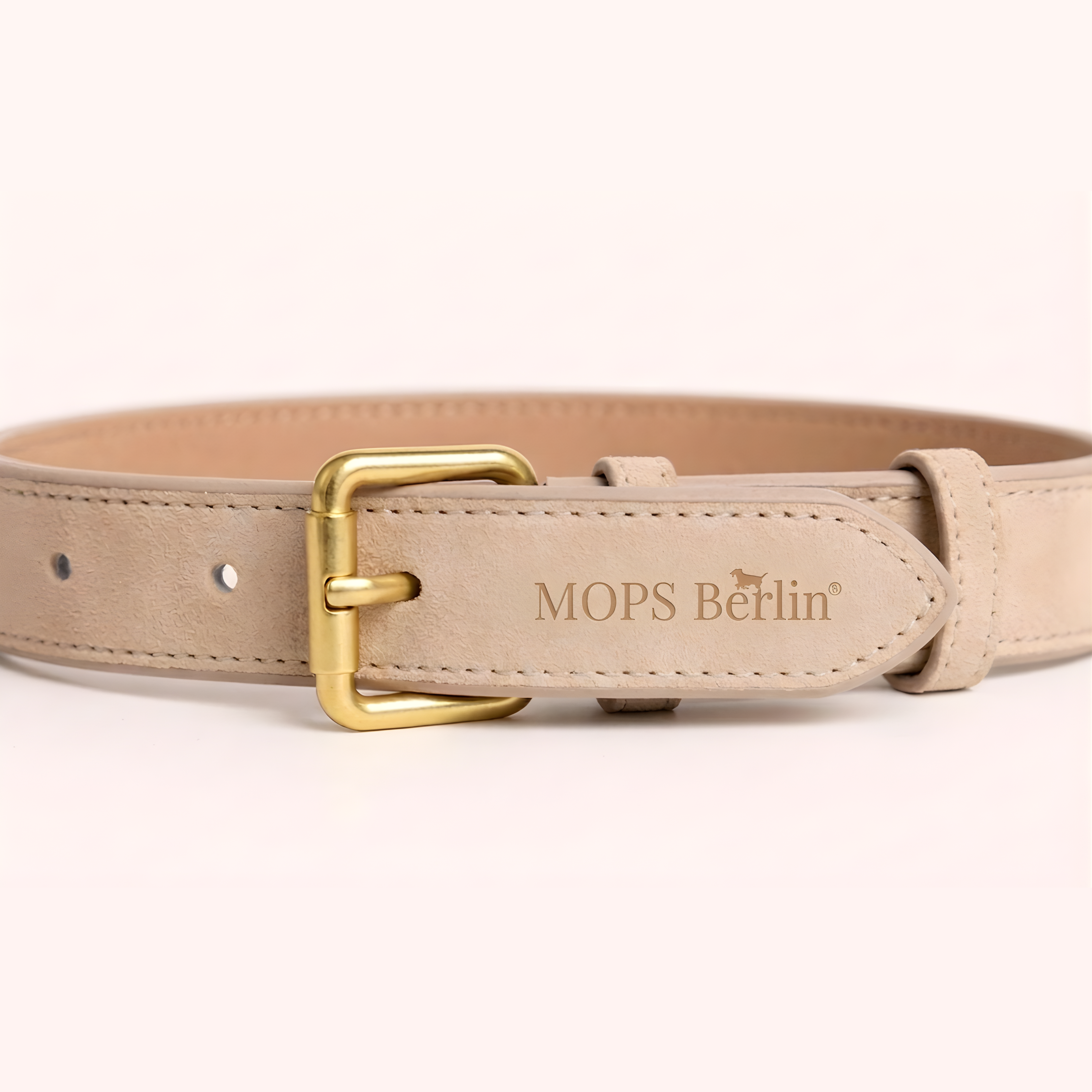 Nahaufnahme vom Schnallenende des Mops Berlin Hundehalsbands Goldküste aus beige-cremefarbenem veganem Leder mit eingeprägtem Logo und mattgoldener Metallschließe