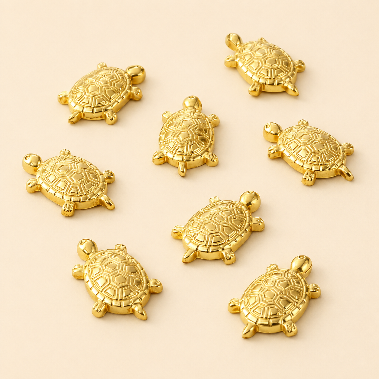 Nahaufnahme von glänzenden, goldfarbenen Schildkröten-Metallbeschlägen des Mops Berlin Designs Goldküste auf beige-cremefarbenem Hintergrund